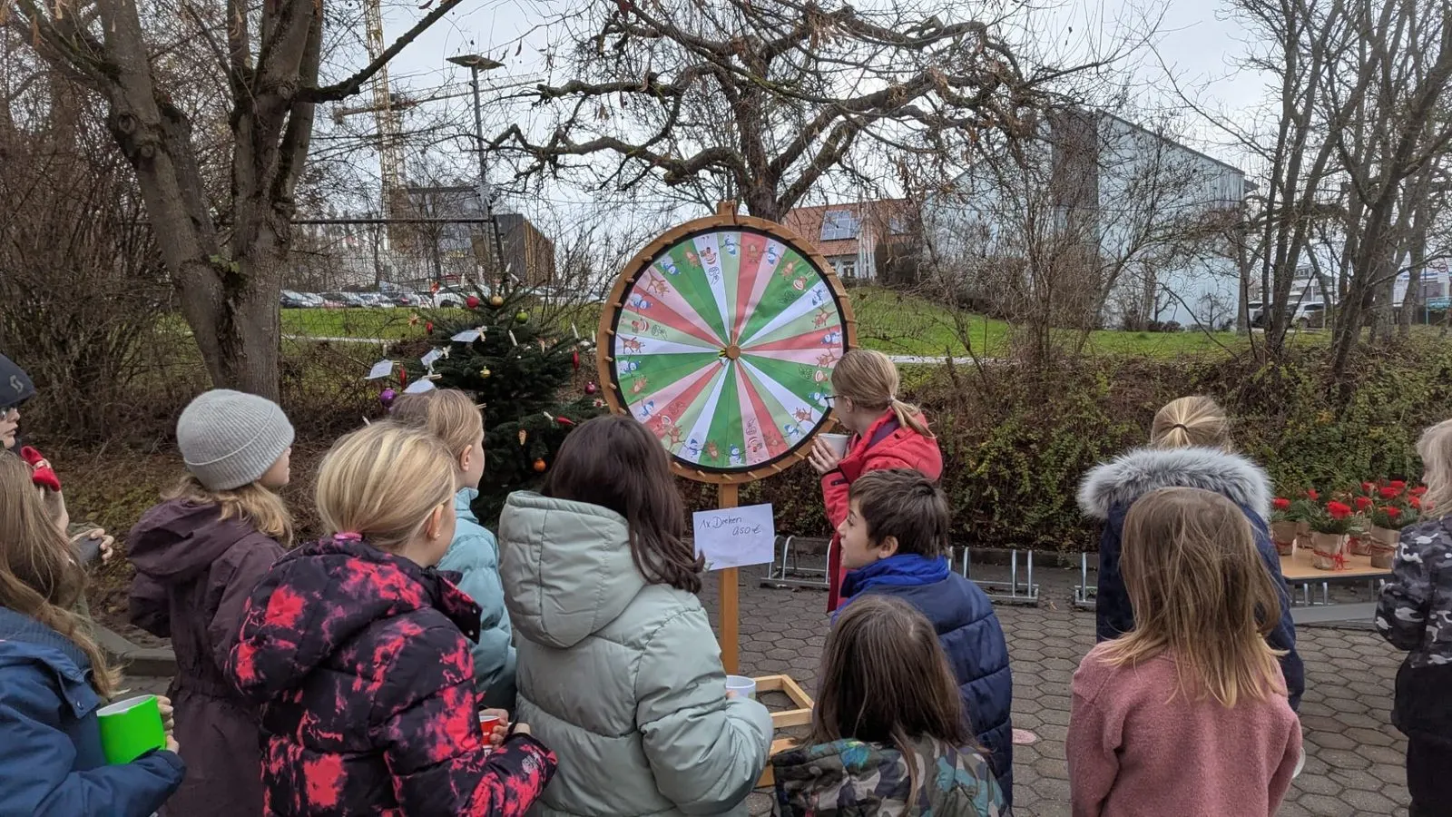 Kinder stehen vor einem bunten Glücksrad im Freien